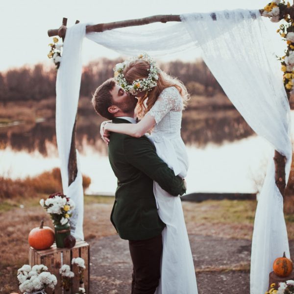 bride and groom kissing in alter against forest and lake background
