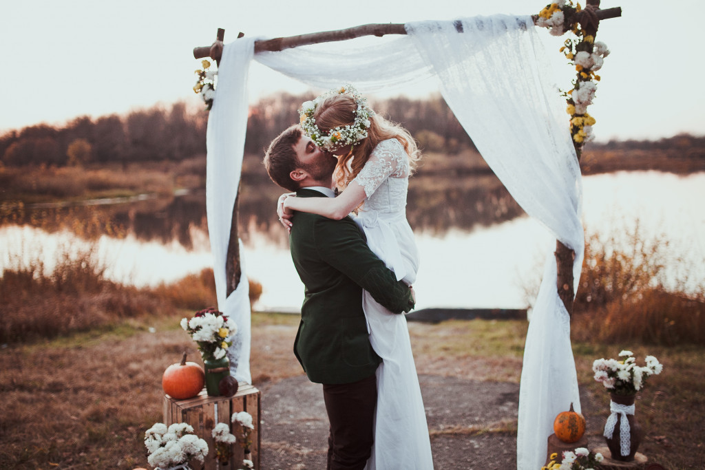 bride and groom kissing in alter against forest and lake background