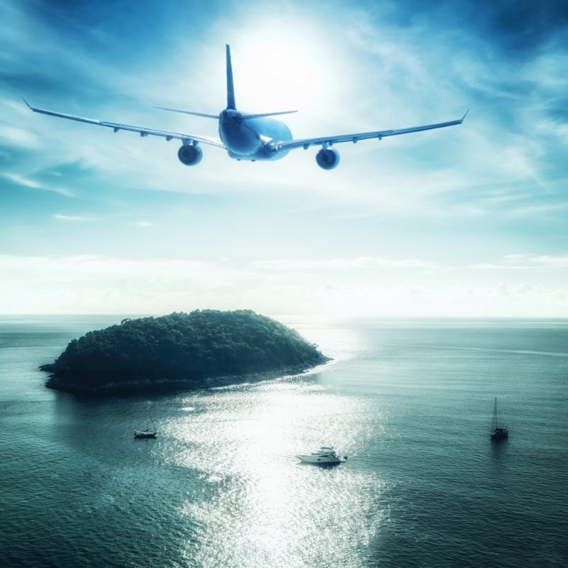 airplane flying over deep ocean with boats and ships