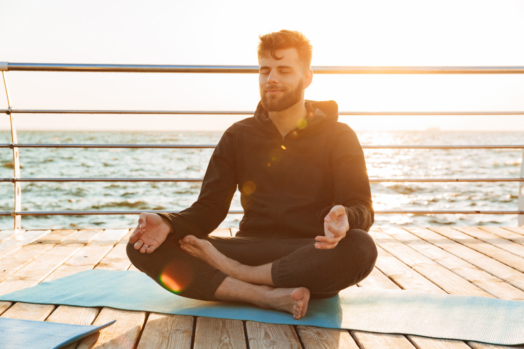 Young man meditating at the beach.