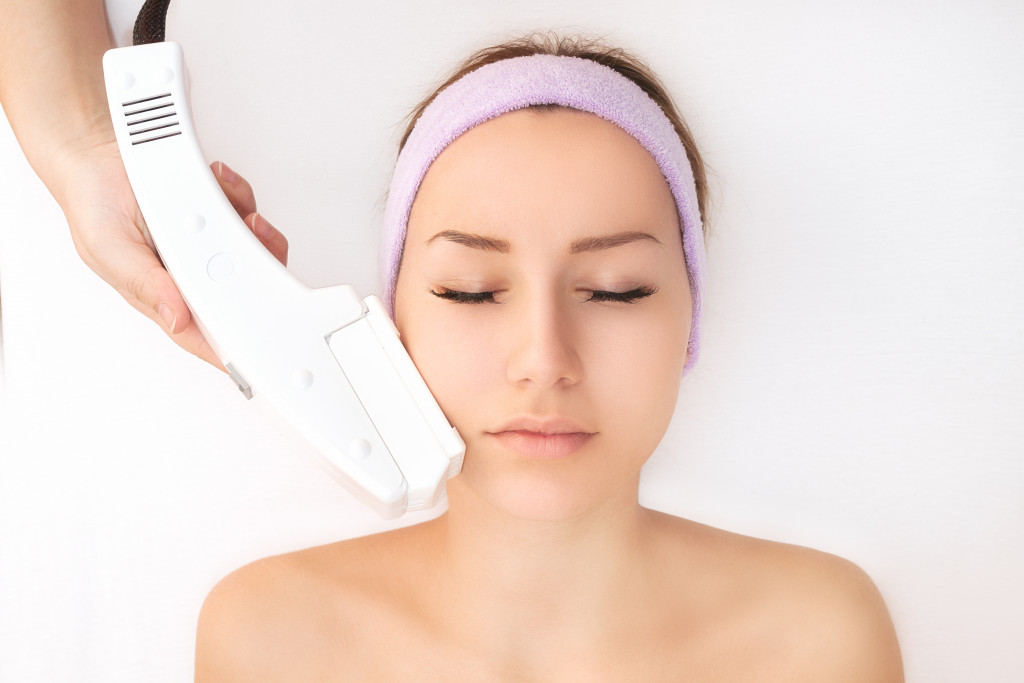 woman getting laser hair removal treatment on her face