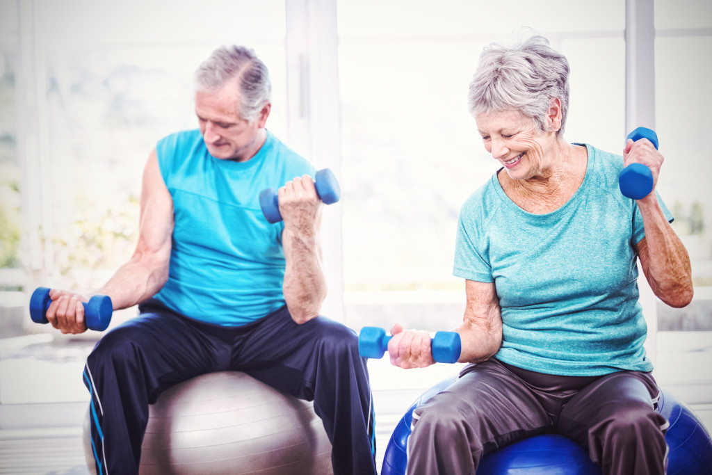 Senior couple exercising at a gym using dumbbells.