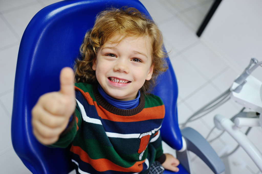 kid smiling while showing teeth and thumbs up