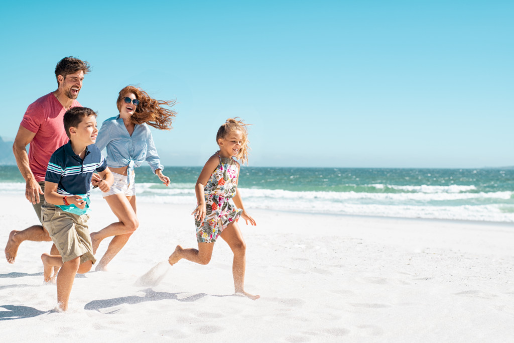 Family running on a beach during summer.