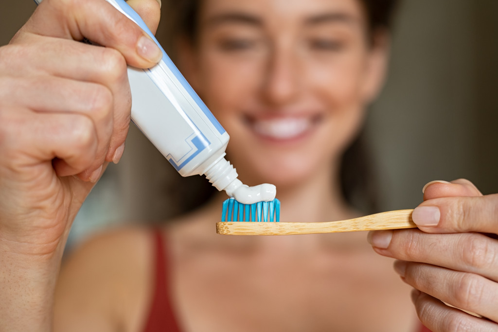 woman putting toothpaste on toothbrush