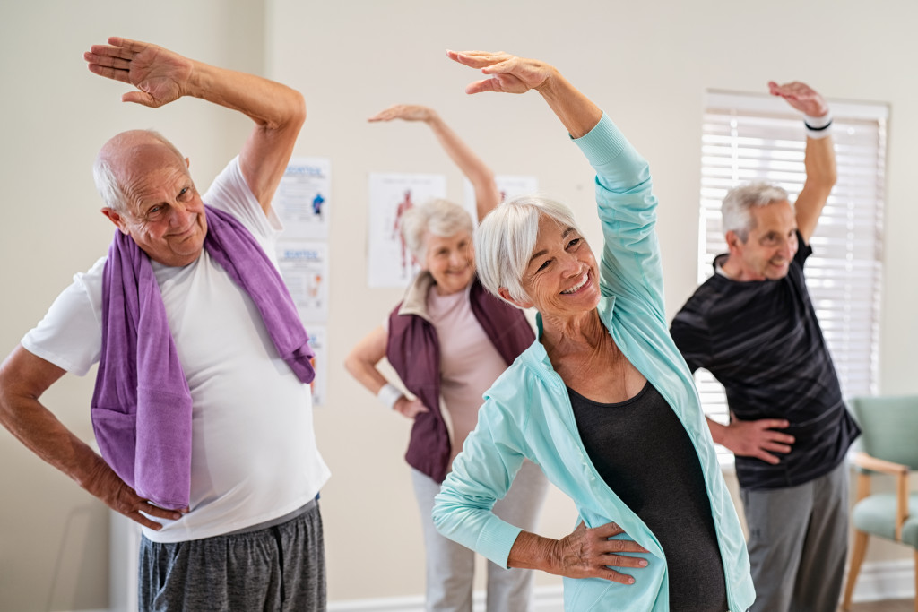Group of senior adults exercising in the living area of a retirement home.