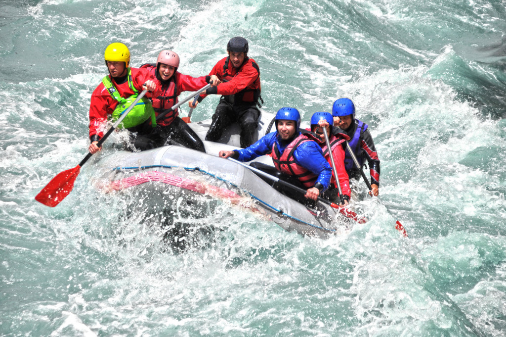 Six adventurers on a raft in a white water river.