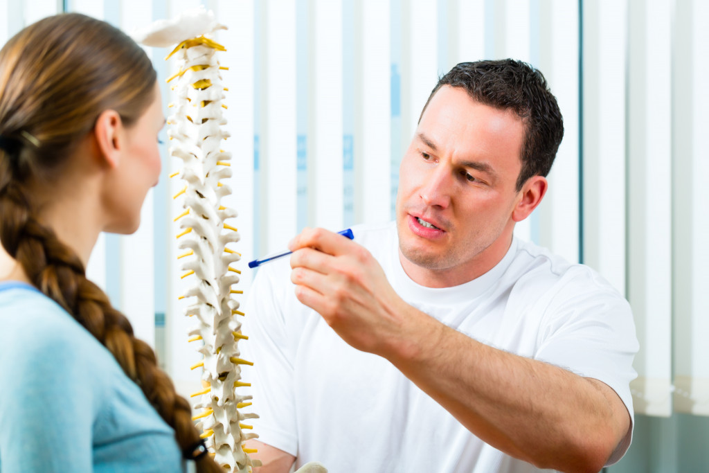 male sports doctor explaining the spine to female patient